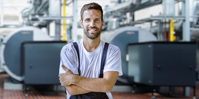 Ein lächelnder Mann in Arbeitskleidung mit verschänkten Armen