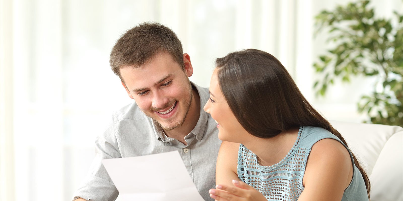 Ein Mann und eine Frau lachen sich an und halten ein Blatt in der Hand